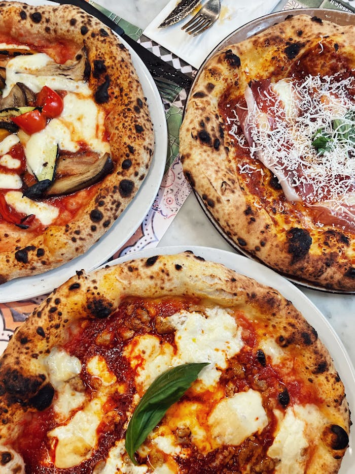 A top view shot of three delicious Neapolitan pizzas with various toppings, perfect for food lovers.